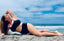 A woman confidently laying on the beach, showing how comfortable and supported she feels in her black Vie Swimwear bikini.