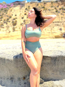 Green swimsuit set with hidden-support top and mid-rise bottom, worn on a sandy beach; fresh, supportive swimwear look.