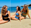 Three women smiling on a sandy beach in stylish, supportive Vie Swimwear — black, blue, and green suits designed for confidence and comfort.
