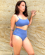 Woman wearing cornflower blue bikini top and high-waisted bottoms, standing against a textured stone wall.