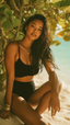 Confident woman wearing a black bikini, seated on a sandy beach with tropical greenery in the background — showcasing Vie Swimwear.